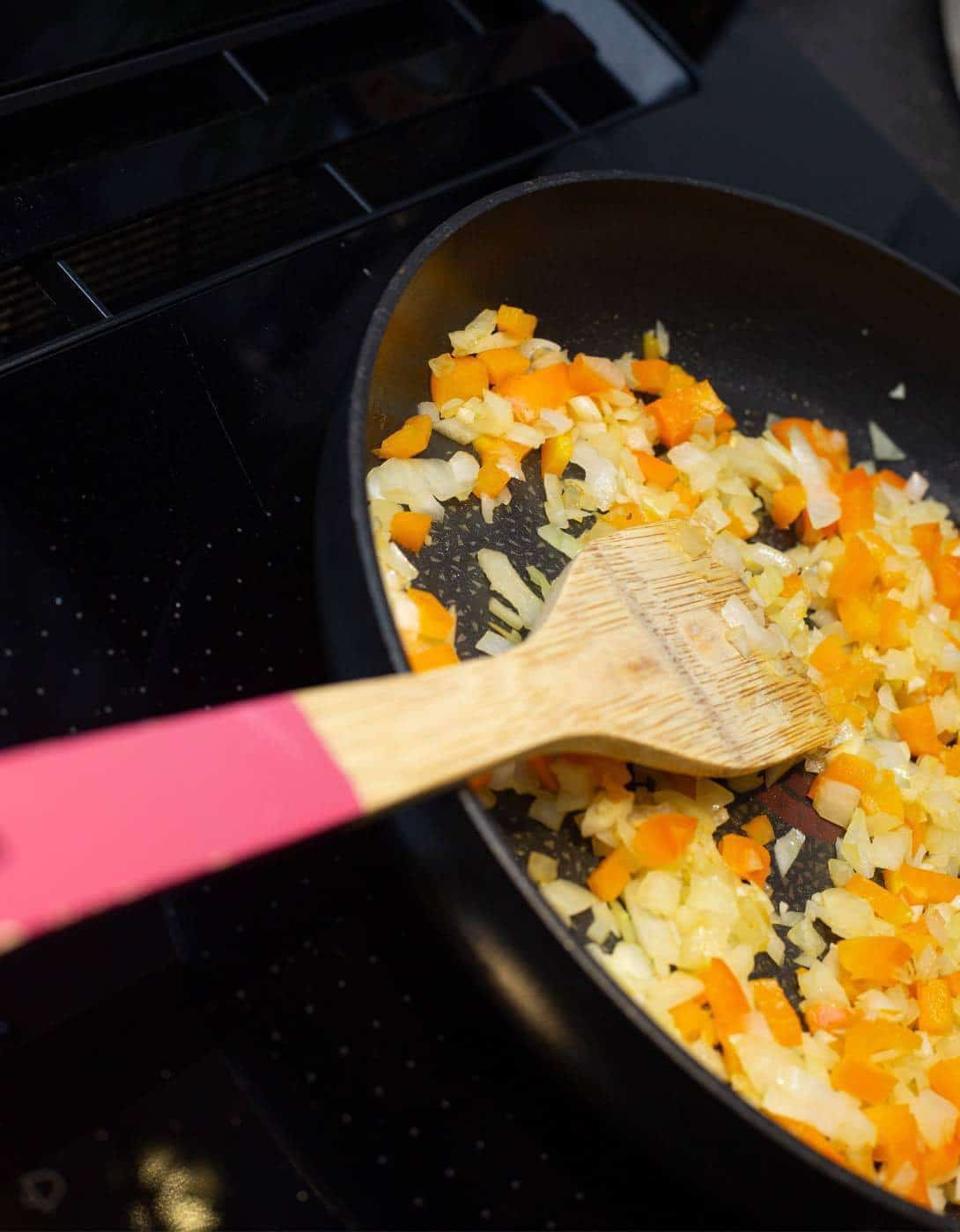 De ui, knoflook en paprika in de pan