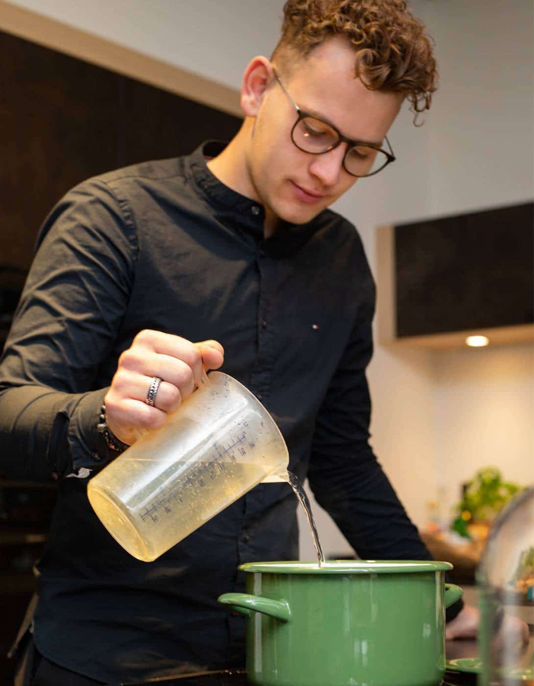 Martijn voegt kippenbouillon toe aan de Thaise kippensoep