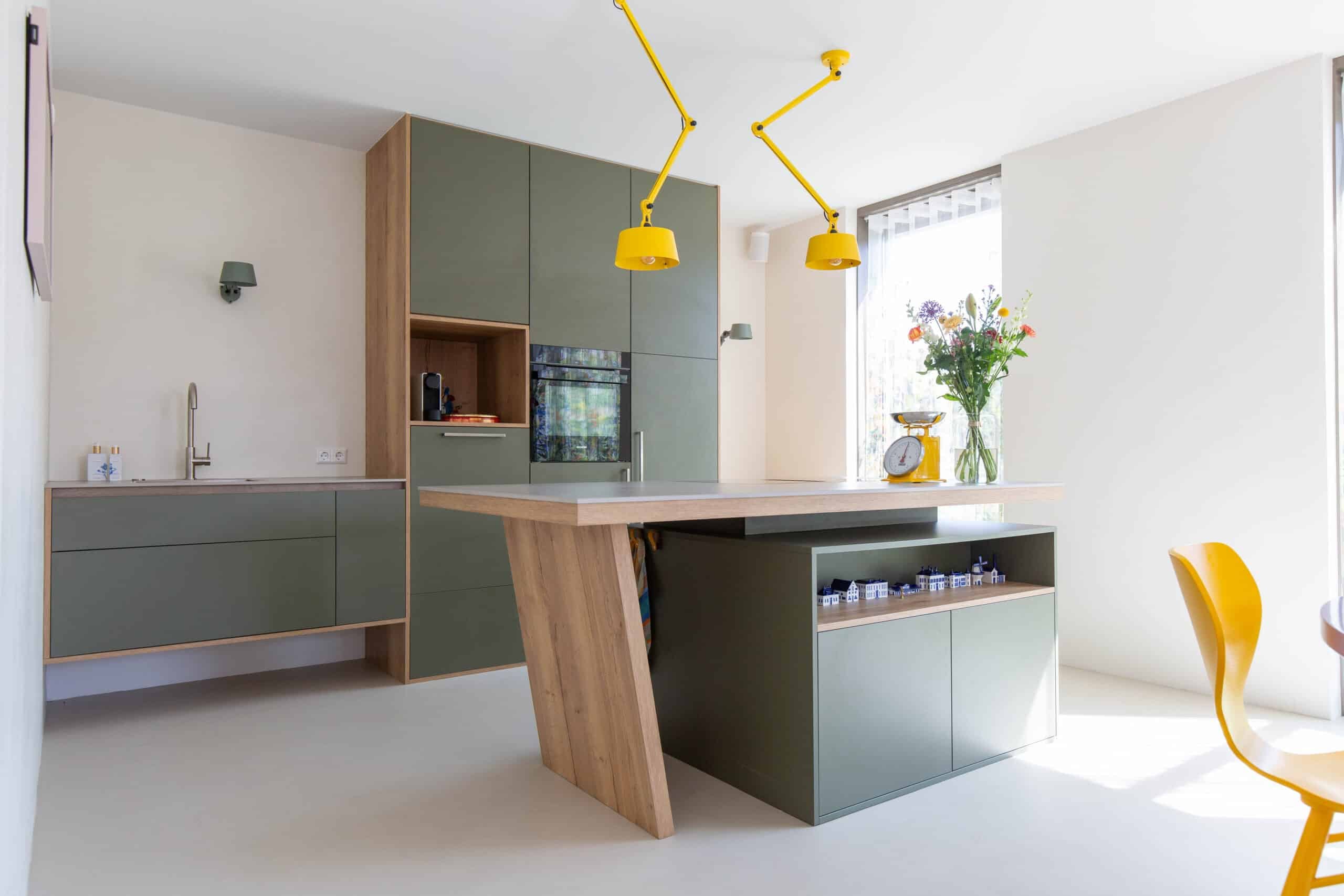 Groene eilandkeuken met kooktafel in een nieuwbouwwoning in Nijkerk